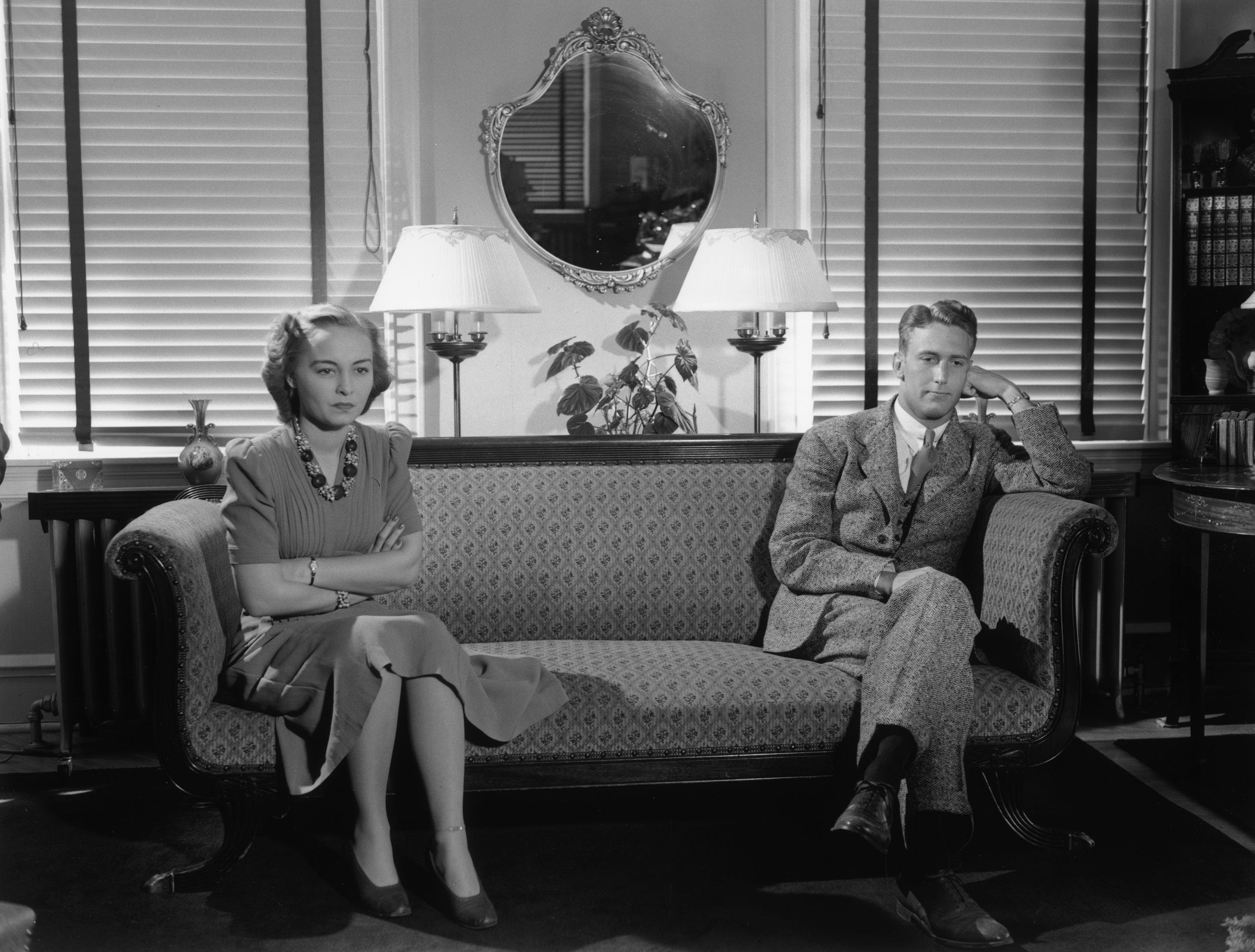 Woman and man sitting at opposite ends of couch.