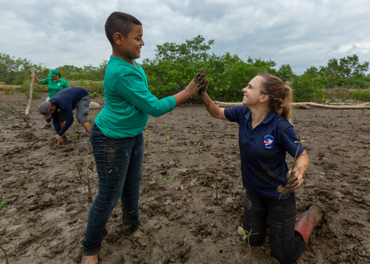 Peace Corps Volunteer high fives Panamanian Child as they work on planting trees