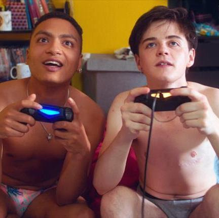 Two young people play video games in their boxers
