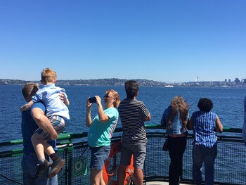 Several people on the outdoor deck of a ferry on a sunny day