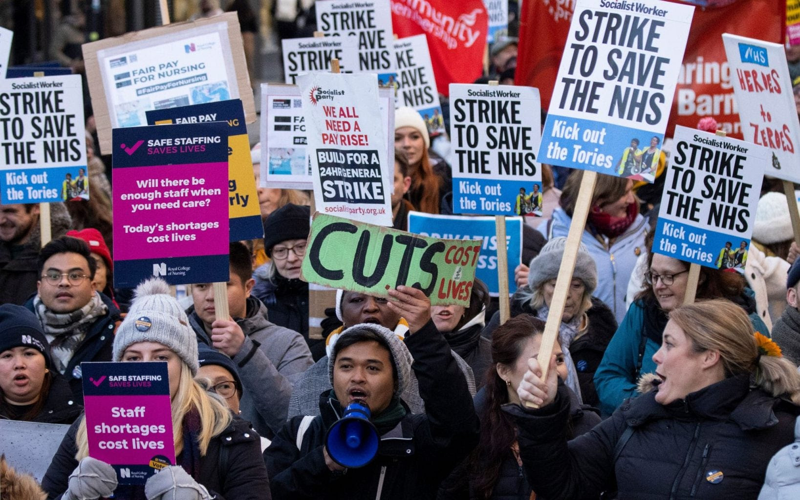 A crowd of protestors holding signs such as 'save the NHS'