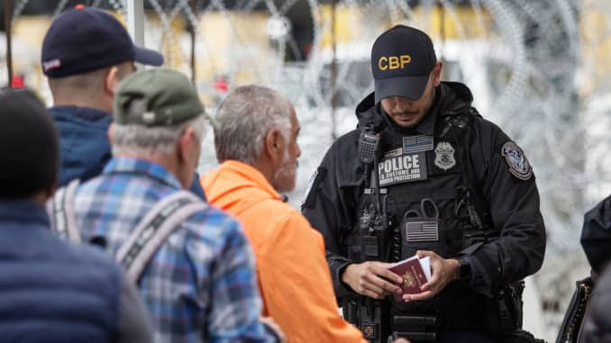 Um oficial de fronteira verifica um passaporte no cruzamento da fronteira entre Tijuana e os EUA.