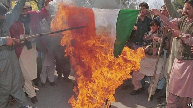 A group of pro-Kashmir supporters give a cheer as the Indian national flag is burnt during a small rally to observe solidarity day near the Indian High Commission in Islamabad, Saturday, Feb. 5, 2000. 