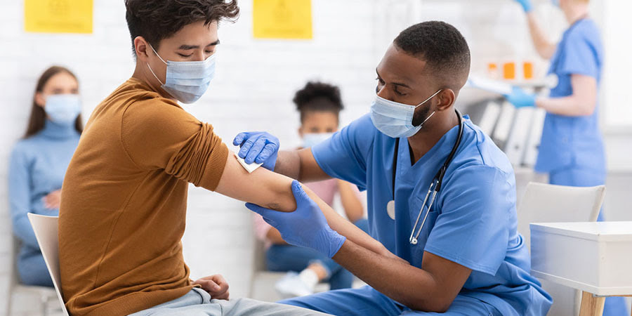 Imagen de un joven recibiendo una vacuna en un hospital 