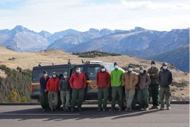 Forest Rangers and volunteers pose for a group photo with mountain range in the background