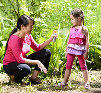 Mother putting bug spray on daughter
