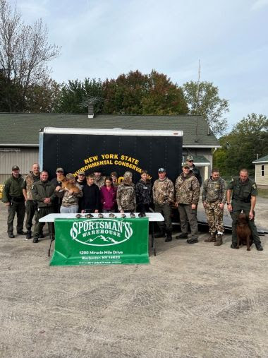 ECOs and youth hunters stand behind table with waterfowl and pheasants they hunted on it