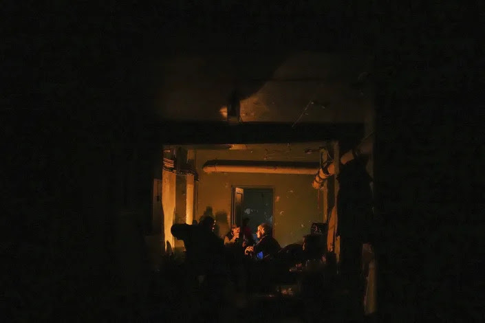 People sit in a dark bomb shelter in Mariupol. 