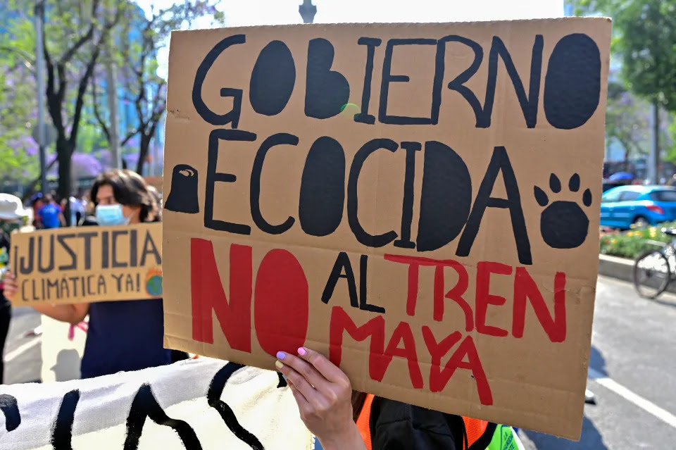 A demostrator holds up a sign reading Ecocidal government, no to the Mayan train during the Fridays for Future global protest in Mexico City, on March 25, 2022. - Activists took to squares around the world for a global climate strike on March 25, 2022, as part of the Fridays For Future movement, led by Swedish Greta Thunberg. (Photo by PEDRO PARDO / AFP) (Photo by PEDRO PARDO/AFP via Getty Images)