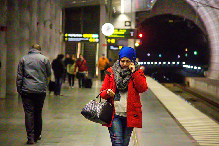 mulher andando e falando ao telefone em uma estação de metrô à noite