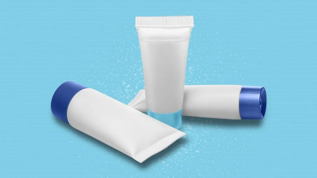 Tubes of genital wart treatments like lotions and ointment on blue background