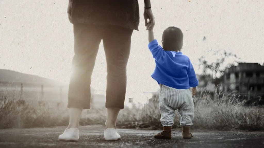 A caregiver holding the hand of a baby who might be autistic.