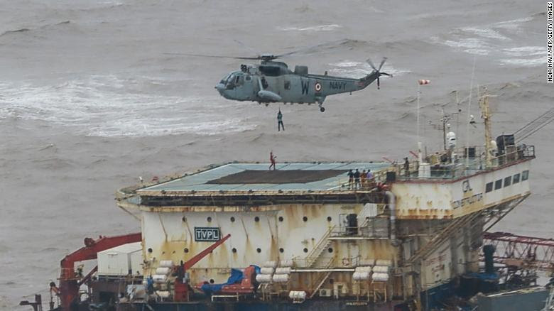 Stranded people on a barge in the middle of the ocean being rescued by a helicopter 