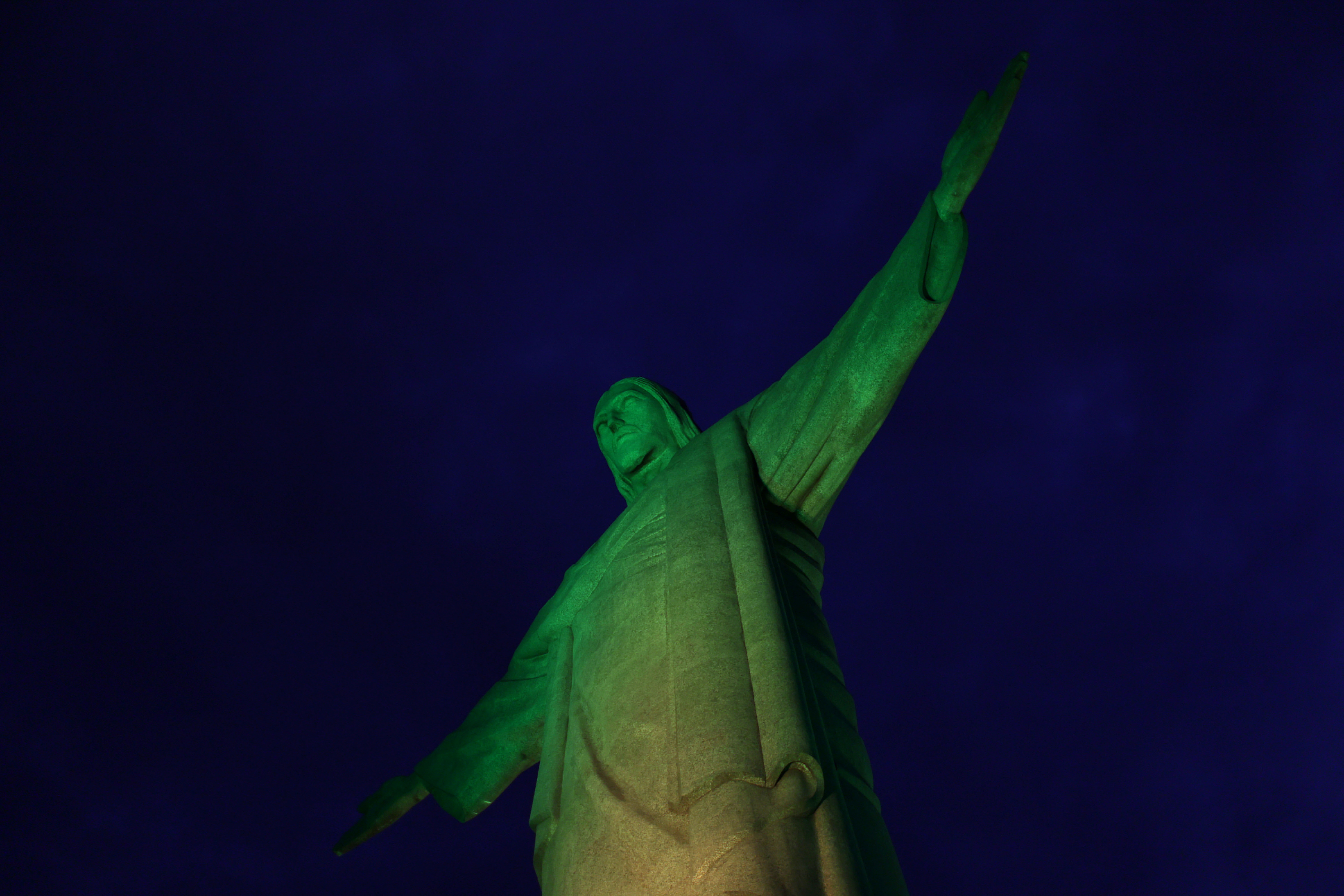 The statue of Christ the Redeemer is lit up with the Brazilian flag colors to celebrate the national soccer team's victory in the FIFA World Cup match against South Korea, in Rio de Janeiro, Brazil December 5, 2022. REUTERS/Pilar Olivares