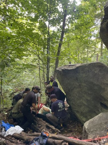 Rangers and EMS assisting injured hiker into a litter