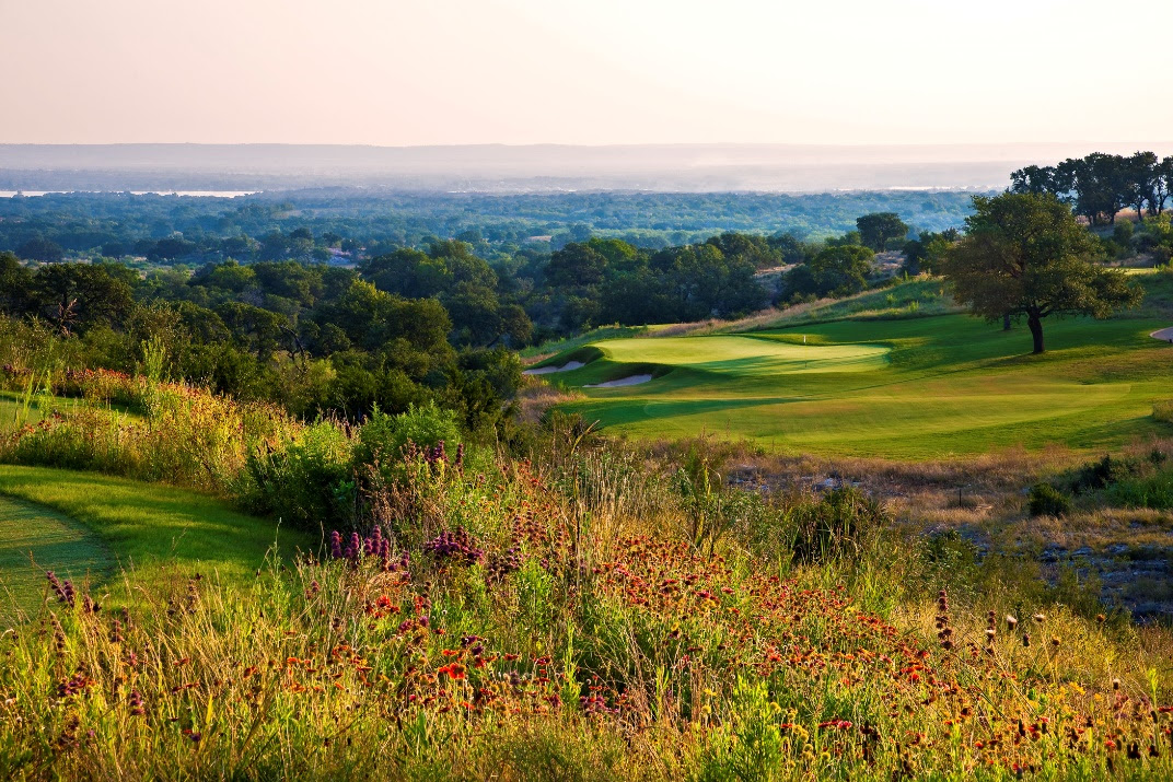 A golf course with trees and a body of water

Description automatically generated