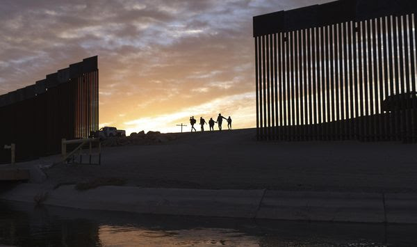 In this Thursday, June 10, 2021, photo, a pair of migrant families from Brazil pass through a gap in the border wall to reach the United States after crossing from Mexico to Yuma, Ariz., to seek asylum. (AP Photo/Eugene Garcia) **FILE**