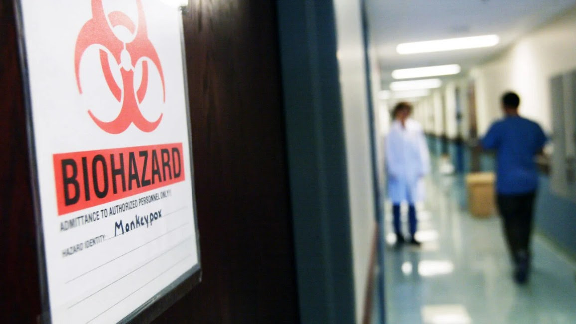 A biohazard sign for monkey pox is scene in a hallway.