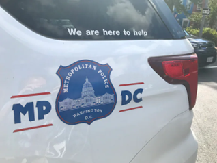 Side profile of a DC Metropolitan Police Car. Text reads: “We are here to help” above the Metropolitan Police logo. 