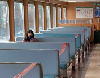 Photo of person wearing a face mask while sitting in booth aboard a ferry