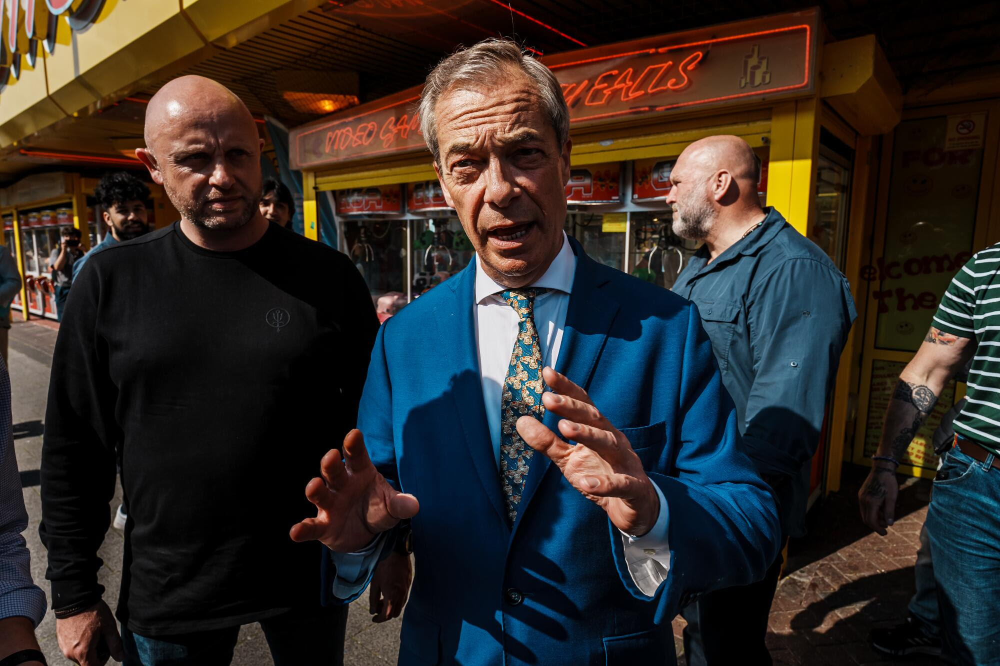 Nigel Farage gestures in a bright blue suit.