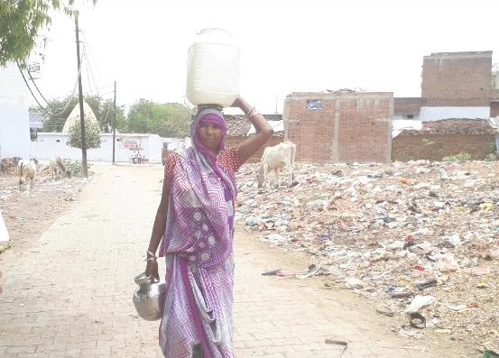झांसी के गांव में महिला कई किलोमीटर दूर से पानी भर कर लाती हुई/प्रशांत श्रीवास्तव/दिप्रिंट