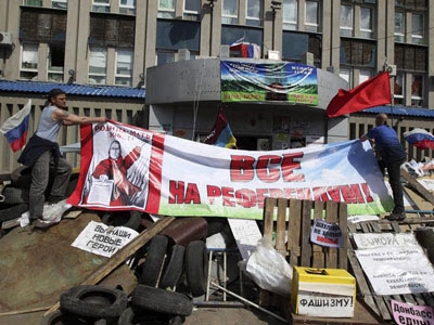 Activistas colocan una pancarta para pedir la convocatoria de un referéndum sobre el estatus de la región delante de la sede del Servicio de Seguridad, ocupada por activistas prorrusos, en Lugansk (Ucrania)