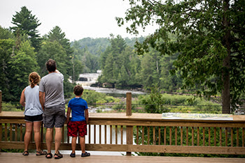 Man and two kids on platform overlooking Lower Tahquamenon Falls