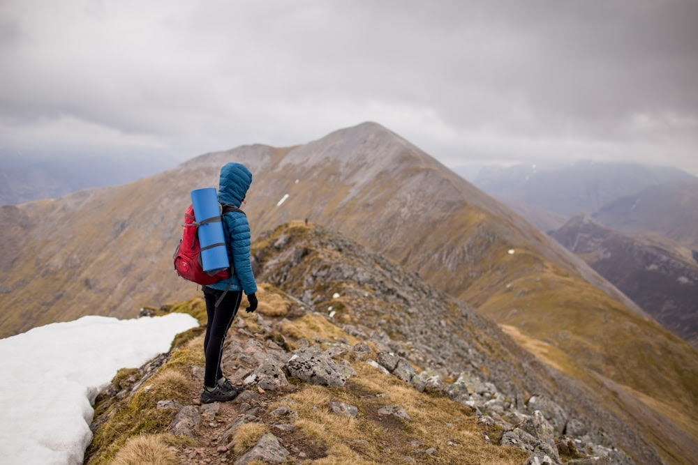 persona in cima alla montagna con zaino rosso