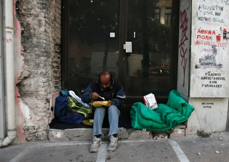 homeless man eats doorway closed shop Athens.