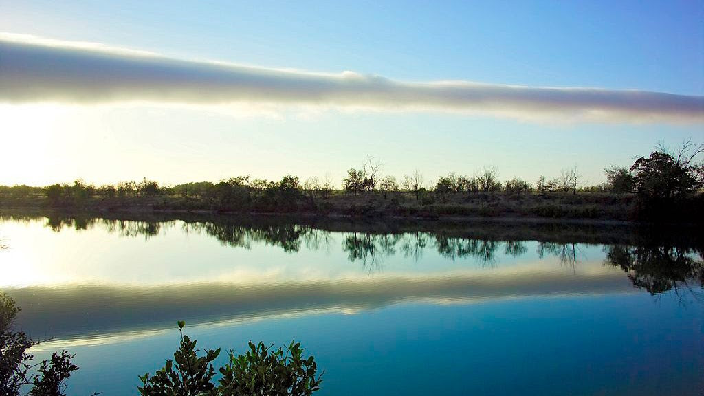 a long thin cloud above a river.
