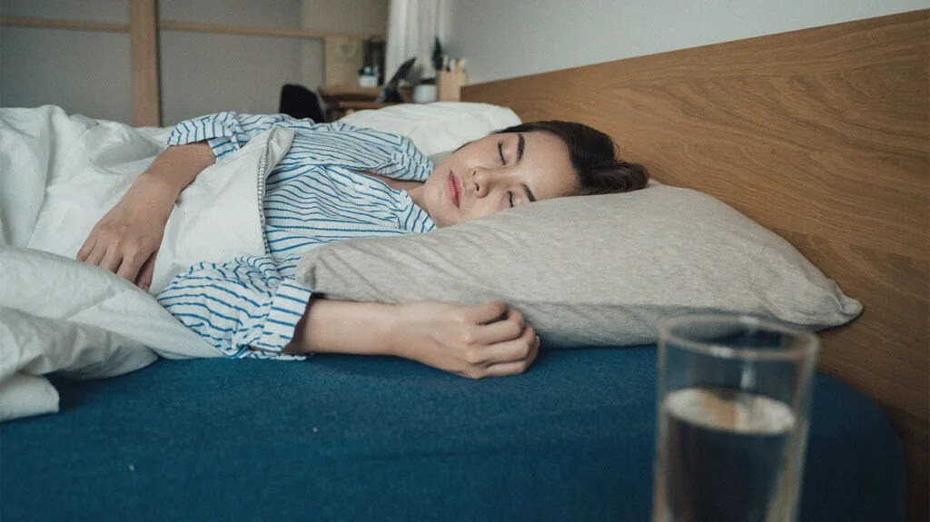 A person wearing blue and white striped pijamas lying in bed.