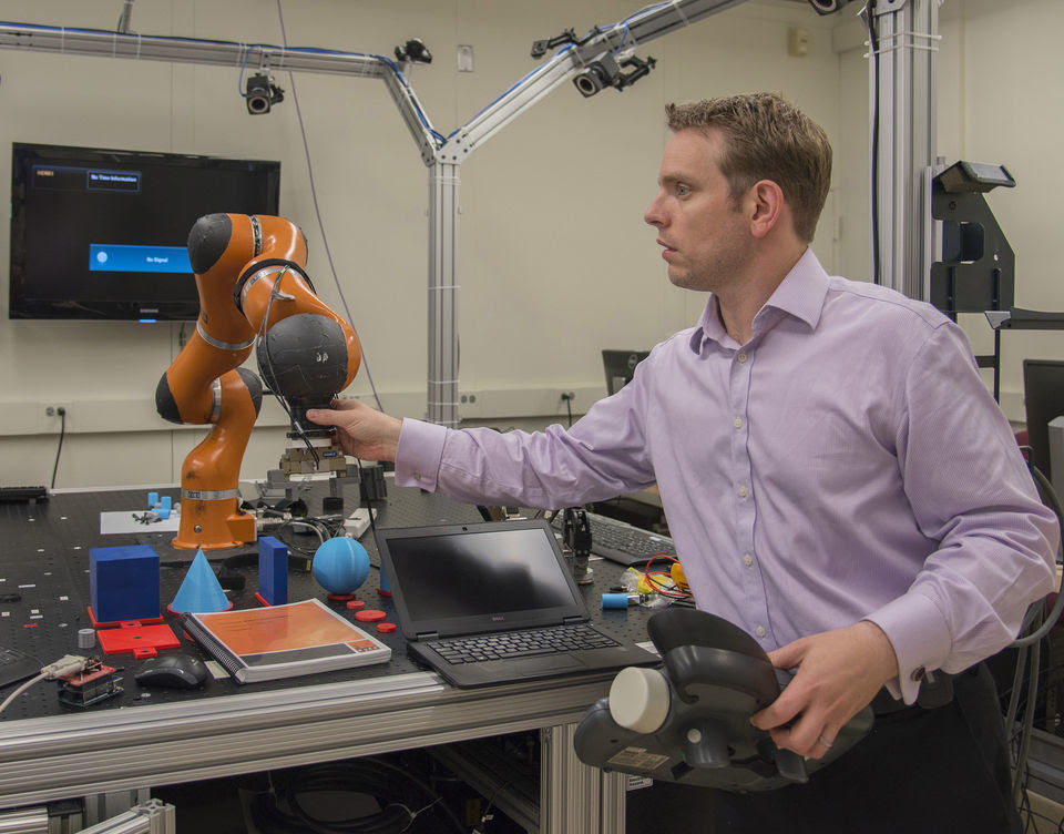 NIST engineer Jeremy Marvel adjusts a robotic arm used to study human-robot interactions