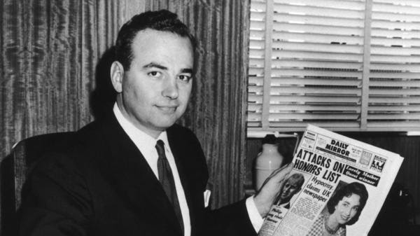 Rupert Murdoch holds up a newspaper