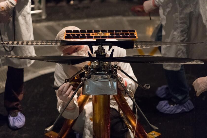 NASA engineers cover the main body of the Mars Helicopter in a protective thermal film