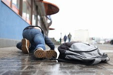 Man with backpack felling on slippery sidewalk in winter 