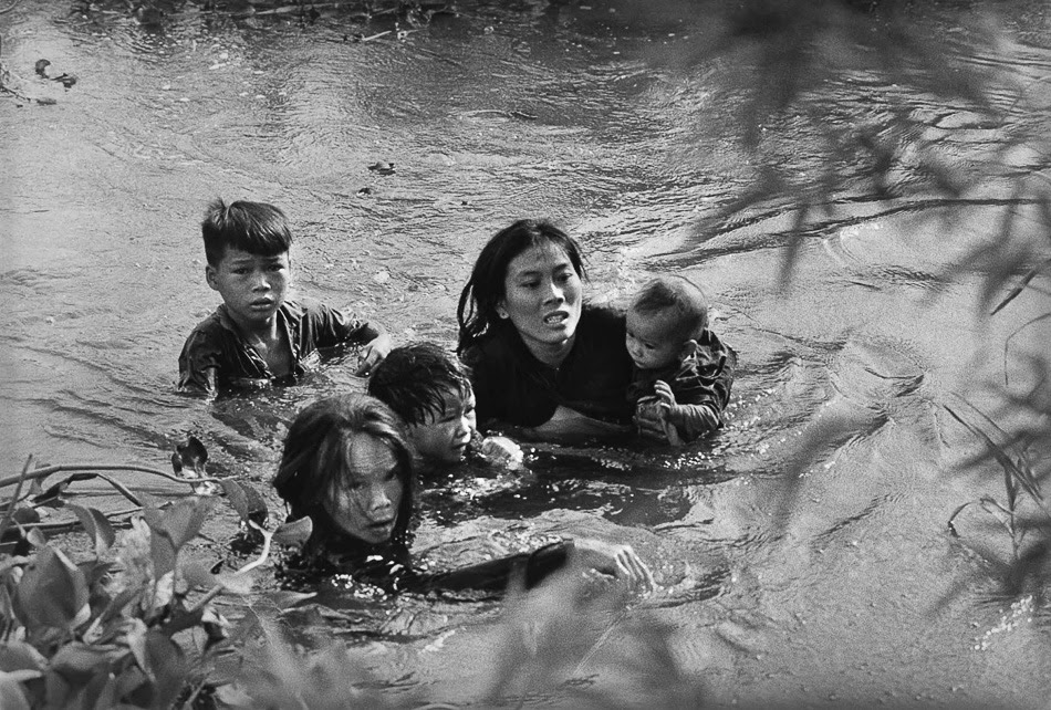 Kyo?ichi Sawada (Japan), A mother and her children wade across a river in Vietnam to escape US bombing, 1965.