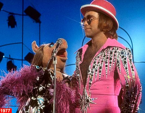 A much slimmer Elton in pink and rhinestone wows Miss Piggy during his appearance on The Muppet Show