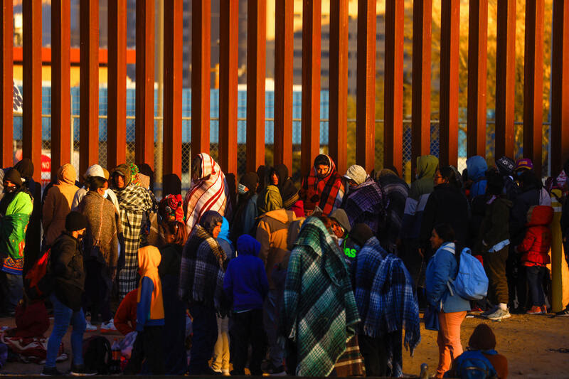 Migrants queue near the border fence, after crossing the Rio Bravo river, to turn themselves in to U.S. Border Patrol agents and request asylum in El Paso, Texas, U.S., as seen from Ciudad Juarez, Mexico December 21, 2022. REUTERS/Jose Luis Gonzalez