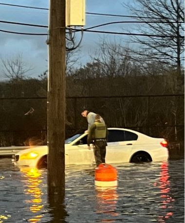 ECO stands next to a car in knee-deep water during flooding