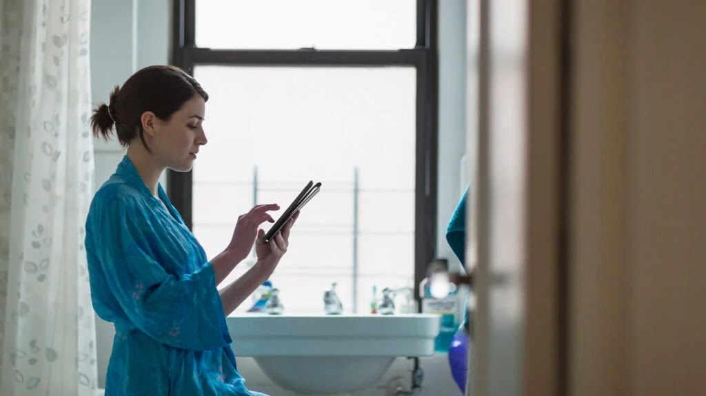 Female in a bathroom using a tablet to look up vaginal infections.