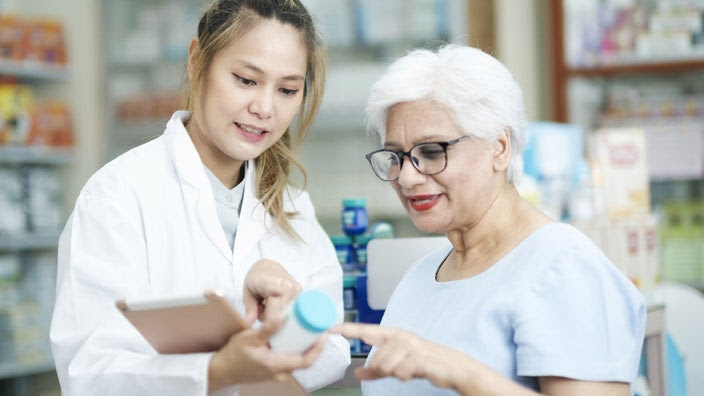 A pharmacist and a patient discussing a pill bottle.