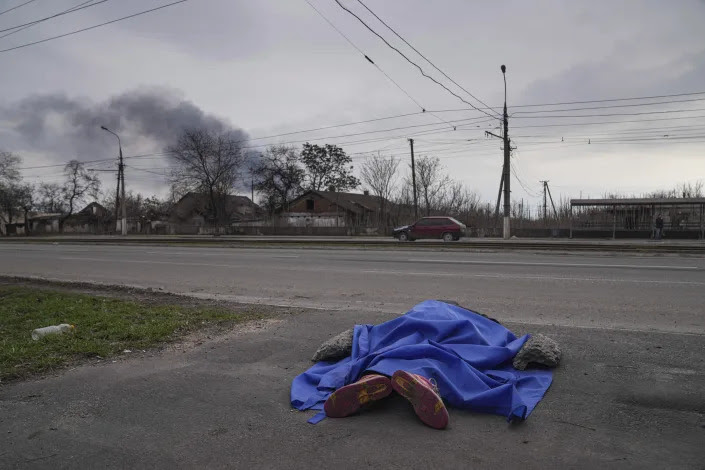 The dead body of a person lies covered in the street in Mariupol. 