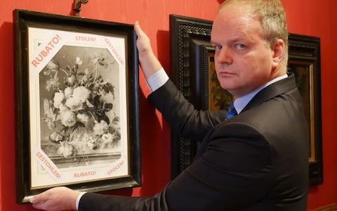 Eike Schmidt, the German director of the Uffizi Galleries, with a black and white photograph of the stolen painting