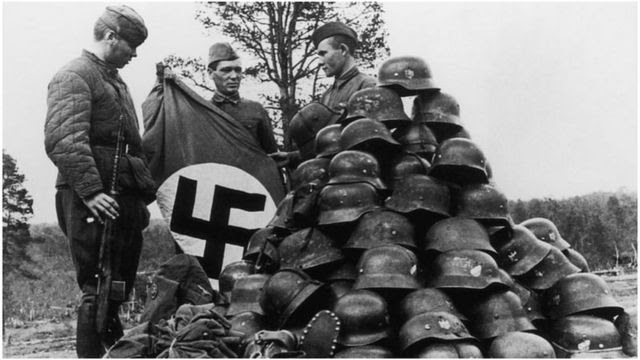 Soviet soldiers stack objects captured from their German enemies in Murmansk, Russia.