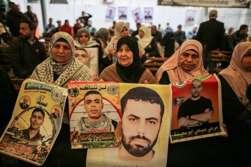 A group of people, holding photos of Palestinian prisoners, gather outside the International Committee of the Red Cross building to support Palestinian prisoners in Israeli jails in Gaza City, Gaza on January 02, 2023. [Ali Jadallah - Anadolu Agency]