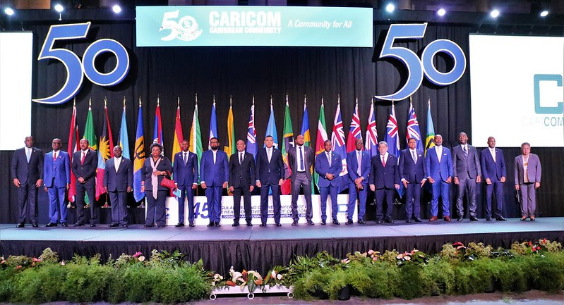 A group of men standing on a stage with flagsDescription automatically generated