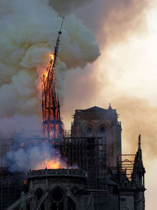 Slide 13 of 31: The steeple of the landmark Notre-Dame Cathedral collapses as the cathedral is engulfed in flames in central Paris on April 15, 2019. - A huge fire swept through the roof of the famed Notre-Dame Cathedral in central Paris on April 15, 2019, sending flames and huge clouds of grey smoke billowing into the sky. The flames and smoke plumed from the spire and roof of the gothic cathedral, visited by millions of people a year. A spokesman for the cathedral told AFP that the wooden structure supporting the roof was being gutted by the blaze. (Photo by Geoffroy VAN DER HASSELT / AFP) (Photo credit should read GEOFFROY VAN DER HASSELT/AFP/Getty Images)